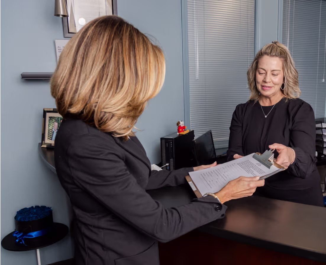 Receptionist handing clipboard to patient at front desk