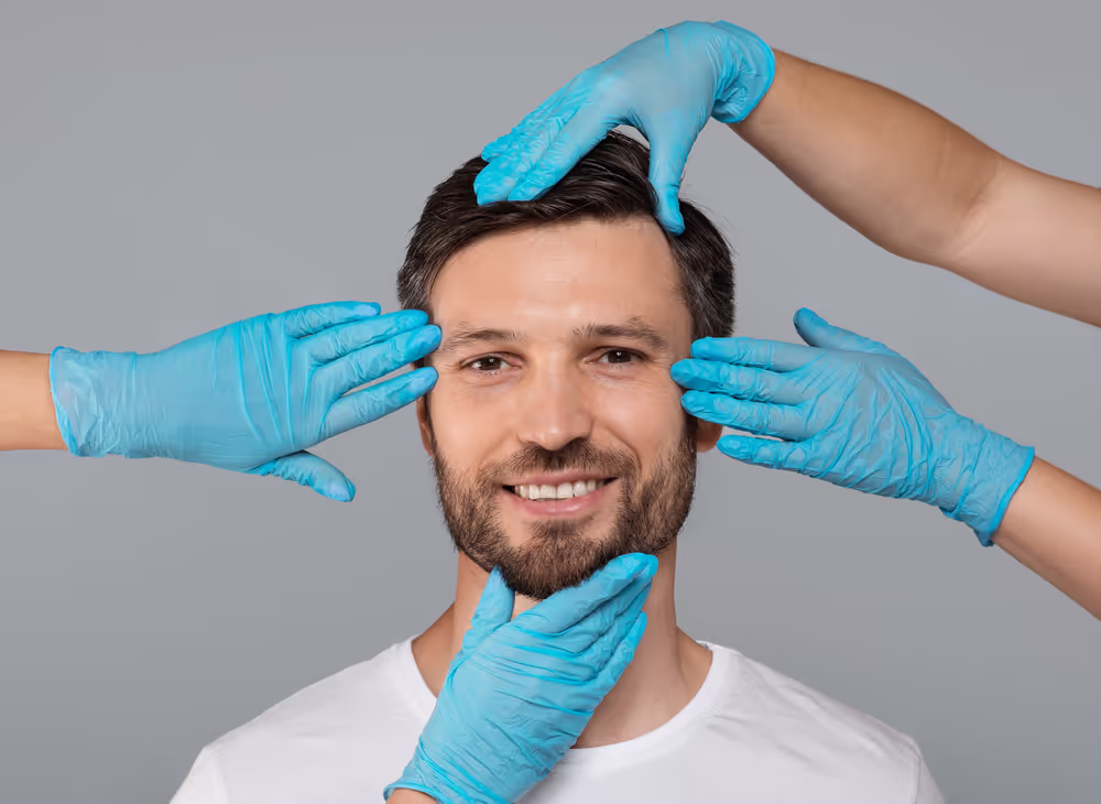 Smiling man’s face examined by gloved hands