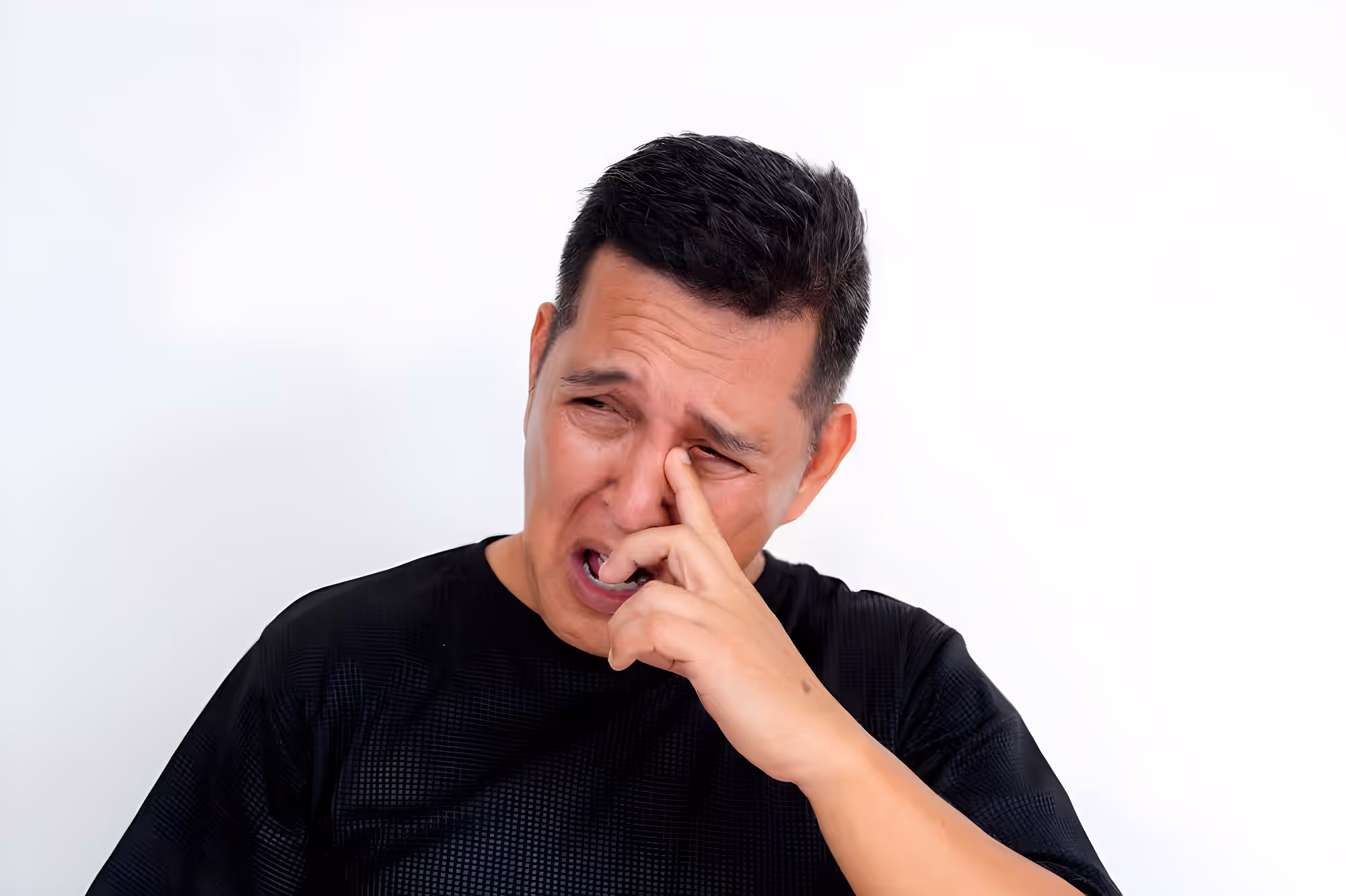 Man rubbing teary eye with uncomfortable expression